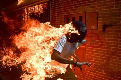  Crise na Venezuela - Imagem de um manifestante venezuelano envolto em chamas durante uma manifestação de protesto em Caracas. Foto feita em 03 de maio de 2017 pelo fotógrafo Ronaldo Schemidt da Agência France Press, baseado  no México mas de nacionalidade Venezuelana.