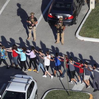 PARKLAND, FL - FEBRUARY 14: People are brought out of the Marjory Stoneman Douglas High School after a shooting at the school that reportedly killed and injured multiple people on February 14, 2018 in Parkland, Florida. Numerous law enforcement officials continue to investigate the scene.   Joe Raedle/Getty Images/AFP