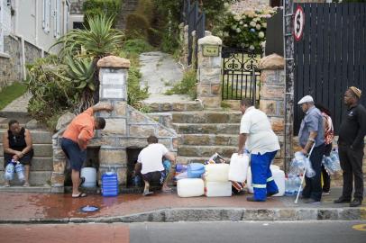  (FILES) This file photo taken on January 19, 2018 shows people collecting drinking water from pipes fed by an underground spring, in St James, about 25km from the city centre in Cape Town. Residents of Cape Towns Nazareth House, a care home for dozens of vulnerable, disabled and orphaned children, are among the citys most vulnerable people. They now face the prospect that the water supply they depend on could be shut off within months as the three-year-long drought -- the worst in a century -- causes dam levels to dip below usable levels. / AFP PHOTO / RODGER BOSCHEditoria: DISLocal: CAPE TOWNIndexador: RODGER BOSCHSecao: droughtFonte: AFPFotógrafo: STR