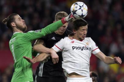 Manchester Uniteds Spanish goalkeeper David De Gea (L) and Manchester Uniteds English midfielder Scott McTominay (C) vie with Sevillas French defender Clement Lenglet during the UEFA Champions League round of 16 first leg football match Sevilla FC against Manchester United at the Ramon Sanchez Pizjuan stadium in Sevilla on February 21, 2018. / AFP PHOTO / JORGE GUERRERO