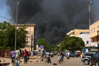  People watch as black smoke rises as the capital of Burkina Faso came under multiple attacks on March 2, 2018, targeting the French embassy, the French cultural centre and the countrys military headquarters.Witnesses said five armed men got out of a car and opened fire on passersby before heading towards the embassy, in the centre of the city. Other witnesses said there was an explosion near the headquarters of the Burkinabe armed forces and the French cultural centre, which are located about a kilometre (half a mile) from the site of the first attack. / AFP PHOTO / Ahmed OUOBAEditoria: POLLocal: OuagadougouIndexador: AHMED OUOBASecao: diplomacyFonte: AFPFotógrafo: STR