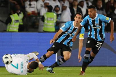 Real Madrids Cristiano Ronaldo (L) falls to the ground as Germios captain Pedro Geromel and Brazilian player Jailson (R) watch on during the Club World Cup UAE 2017 final football match between Gremio FBPA and Real Madrid at the Zayed Sports City Stadium in Abu Dhabi on December 16, 2017. / AFP PHOTO / KARIM SAHIB