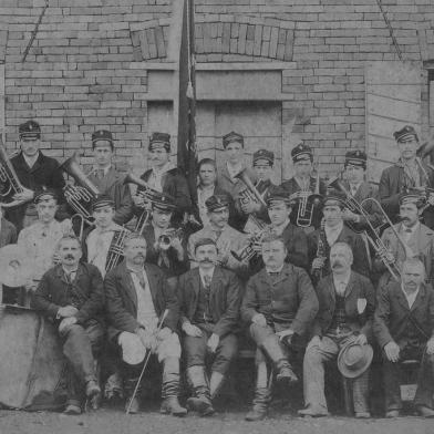 Primeira formação da Banda Santa Cecília, de Caxias do Sul. Ao centro, de pé e roupa clara, o fundador Octaviano Curtolo (Otávio Curtolo). Caxias do Sul, 1890.