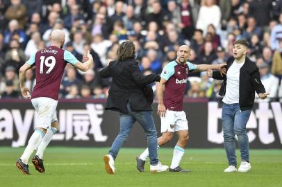 West Ham Uniteds Argentinian defender Pablo Zabaleta (2R) and West Ham Uniteds Welsh defender James Collins (L) interact with pitch invaders during the English Premier League football match between West Ham United and Burnley at The London Stadium, in east London on March 10, 2018. / AFP PHOTO / Ben STANSALL / RESTRICTED TO EDITORIAL USE. No use with unauthorized audio, video, data, fixture lists, club/league logos or live services. Online in-match use limited to 75 images, no video emulation. No use in betting, games or single club/league/player publications.  / 