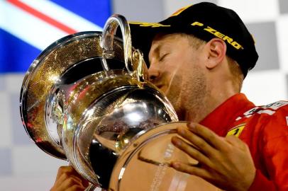 Ferraris German driver Sebastian Vettel kisses his trophy on the podium after winning the Bahrain Formula One Grand Prix at the Sakhir circuit in Manama on April 8, 2018.  / AFP PHOTO / Andrej ISAKOVIC