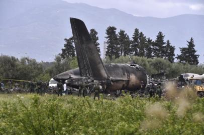 Rescuers are seen around the wreckage of an Algerian army plane which crashed near the Boufarik airbase from where the plane had taken off on April 11, 2018.The Algerian military plane crashed and caught fire killing 257 people, mostly army personnel and members of their families, officials said. / AFP PHOTO / Ryad KRAMDI