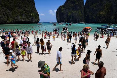  This photo taken on April 9, 2018 shows Thai park rangers keeping watch as tourists walk along the Maya Bay beach, on the southern Thai island of Koh Phi Phi.Across the region, Southeast Asia's once-pristine beaches are reeling from decades of unchecked tourism as governments scramble to confront trash-filled waters and environmental degradation without puncturing a key economic driver. / AFP PHOTO / Lillian SUWANRUMPHA / TO GO WITH AFP STORY "THAILAND-INDONESIA-PHILIPPINES-TOURISM-ENVIRONMENT" by Lillian SUWANRUMPHA with Joe FREEMANEditoria: FINLocal: Ban Ko Phi PhiIndexador: LILLIAN SUWANRUMPHASecao: tourism and leisureFonte: AFPFotógrafo: STF