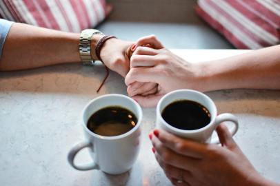 casal conversando tomando um café de mãos dadas