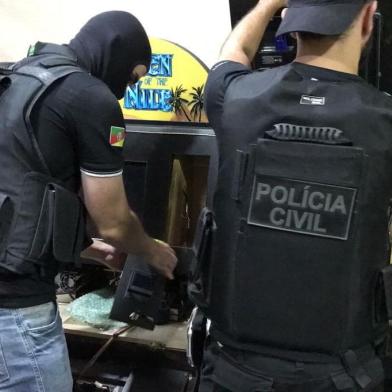 Policiais civis realizaram, na manhã desta sexta-feira (27), uma operação para descapitalizar organização criminosa que explorava jogos de azar e depois lavava dinheiro com imóveis, lojas e veículos no Rio Grande do Sul. Foram cumpridos 32 mandados de busca e apreensão em Porto Alegre, Cachoeirinha, Canoas e Xangri-lá. Além disso, mais de 60 veículos e imóveis foram sequestrados judicialmente. O grupo adquiriu um patrimônio superior a R$ 15 milhões com as atividades ilícitas. Durante o cumprimento dos mandados de busca, os agentes apreenderam armas e localizaram em Canoas um depósito com 200 máquinas caça-níqueis. Três pessoas foram detidas por posse ilegal de arma de fogo. 