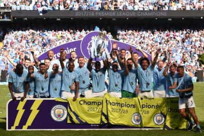 Manchester City players celebrate with the Premier League trophy on the pitch after the English Premier League football match between Manchester City and Huddersfield Town at the Etihad Stadium in Manchester, north west England, on May 6, 2018. / AFP PHOTO / Oli SCARFF / RESTRICTED TO EDITORIAL USE. No use with unauthorized audio, video, data, fixture lists, club/league logos or live services. Online in-match use limited to 75 images, no video emulation. No use in betting, games or single club/league/player publications.  / 