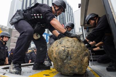 Members of the explosive ordinance disposal unit inspect a defused US-made bomb (C), dropped during World War II, that was found inside a construction site at the junction of Convention Avenue and Hung Hing Road in the Wan Chai district of Hong Kong on May 11, 2018. Hundreds of people were evacuated May 11 after a World War II bomb was found at a Hong Kong construction site, police said, the third such discovery in the territory this year.