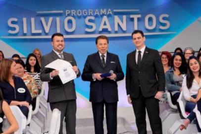 Faustino da Rosa Junior, dono do grupo educacional Facinepe/Inepe, entrega diploma de doutor honoris causa em Comunicação para o comunicador Silvio Santos, dono do canal de televisão SBT, durante programa de auditório do homem do baú. 