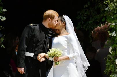 Britains Prince Harry, Duke of Sussex kisses his wife Meghan, Duchess of Sussex as they leave from the West Door of St Georges Chapel, Windsor Castle, in Windsor, on May 19, 2018 after their wedding ceremony. / AFP PHOTO / POOL / Ben Birchall