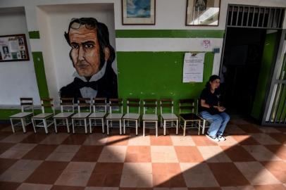 A Venezuelan woman waits at an empty polling station during the presidential elections in Caracas on May 20, 2018 Venezuelans, reeling under a devastating economic crisis, began voting Sunday in an election boycotted by the opposition and condemned by much of the international community but expected to hand deeply unpopular President Nicolas Maduro a new mandate / AFP PHOTO / Juan BARRETO