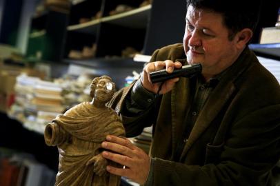 PORTO ALEGRE, RS, BRASIL, 22-05-2018: O professor doutor da escola de Humanidades e coordenador do Projeto de Arte Sacra Jesuítico-Guarani da Pucrs, Edison Hüttner, examina estátua de São Pedro na universidade. Hüttner já identificou inúmeras peças que são relíquias históricas do Rio Grande do Sul. A mais recente delas é essa estátua de São Pedro, que ficará em exposição na Pucrs no mês de junho. (Foto: Mateus Bruxel / Agência RBS)