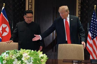  US President Donald Trump (R) gestures as he and North Koreas leader Kim Jong Un arrive for a signing ceremony during their historic US-North Korea summit, at the Capella Hotel on Sentosa island in Singapore on June 12, 2018.Donald Trump and Kim Jong Un became on June 12 the first sitting US and North Korean leaders to meet, shake hands and negotiate to end a decades-old nuclear stand-off. / AFP PHOTO / SAUL LOEBEditoria: POLLocal: SingaporeIndexador: SAUL LOEBSecao: diplomacyFonte: AFPFotógrafo: STF