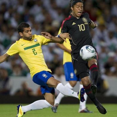 Giovanni Dos Santos (R) of Mexico vies for the ball with Daniel Alves (L) of Brazil during a friendly soccer match in Torreon, Mexico, on October 11,  2011. AFP PHOTO/RONALDO SCHEMIDT