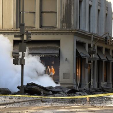 A worker looks at steam coming from 5th Avenue after a steam explosion tore apart the street in the Flatiron District of New York on July 19, 2018. Officials, according to media reports, said firefighters responded and were evacuating buildings near the accident. The Fire Department of the City of New York reported no injuries or deaths. TIMOTHY A. CLARY / AFP