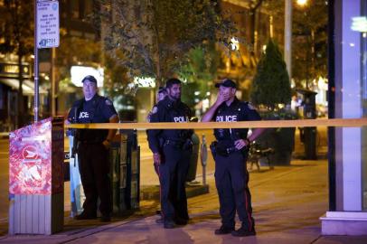 Toronto Police officers stand watch at Danforth St. at the scene of a shooting in Toronto, Ontario, Canada on July 23, 2018.A gunman opened fire in central Toronto on Sunday night, injuring 13 people including a child. Two dead including gunman, police reported. / AFP PHOTO / Cole BURSTON