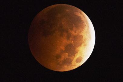 The moon appears to be to have an orange-red hue as the earths shadow covers the moon during a total lunar eclipse, in Griffith Park in Los Angeles, California October 8, 2014. A total lunar eclipse is sometimes called a blood moon because of the red color that is cast upon it by light refracting in Earths atmosphere.   AFP PHOTO / Robyn Beck