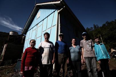  MORRO REUTER, RS, BRASIL, 12-07-2018. Walachai - um lugar longínquo, mas nem tão perdido no tempo. O povoado é formado principalmente por descendentes de imigrantes alemães. A maioria dos moradores aprende o dialeto germânico hunsriqueano riograndense como língua materna e, posteriormente, aprende o idioma português na escola. A região fica localizada a pouco mais de 100km de Porto Alegre. Na foto, a Família Berg:  Heldo Berg, pai, Iara Berg, mãe, e os filhos André, 17 anos, Almir, 15, Alcido Neto (casaco azul), 12, e Aline, 10. Ao fundo, a casa em que moram, construída pelo tataravó de Heldo Berg (no centro, de azul), em 1848. Ela tem 170 anos de existência. (CARLOS MACEDO/AGÊNCIA RBS)Indexador: Carlos Macedo