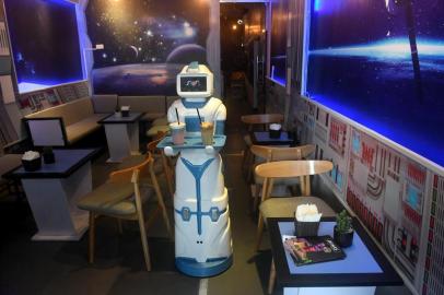 This picture taken on December 11, 2017 shows a robot named Mortar delivering drinks to customers at the Robo Cafe, the first establishment to use a robot in Hanoi.The inspiration for the spaceship-themed cafe, which opened recently in the heart of the citys historic district, came after the owners saw a sushi-serving robot in Japan. Mortar delivers drinks and snacks to customers as it moves across the cafe floor via electromagnetic sensors guided by aluminium strips. / AFP PHOTO / HOANG DINH NAM