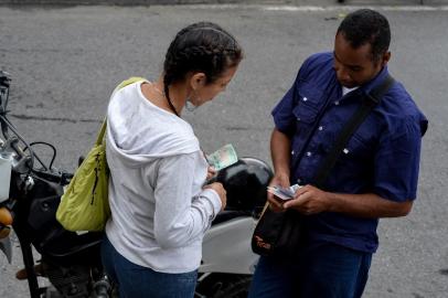 A couple holding new Bolivar-notes talks in downtown Caracas on August 21, 2018. Caracas is issuing new banknotes after lopping five zeroes off the crippled bolivar, casting a pall of uncertainty over businesses and consumers across the country.Federico PARRA / AFP