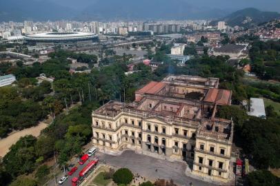 Aerial view of Rio de Janeiros treasured National Museum, one of Brazils oldest, with the Maracana stadium on the background on September 3, 2018, a day after a massive fire ripped through the building. The majestic edifice stood engulfed in flames as plumes of smoke shot into the night sky, while firefighters battled to control the blaze that erupted around 2230 GMT. Five hours later they had managed to smother much of the inferno that had torn through hundreds of rooms, but were still working to extinguish it completely. / AFP PHOTO / Mauro Pimentel