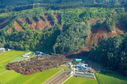 This picture shows an aerial view of houses damaged by a landslide in Atsuma town, Hokkaido prefecture on September 6, 2018, after an earthquake hit the northern Japanese island of Hokkaido.Rescuers scrabbled through mud for survivors after a powerful earthquake sent hillsides crashing down onto homes in Japan, killing at least nine people and leaving dozens of people missing. / AFP PHOTO / JIJI PRESS / JIJI PRESS / Japan OUT