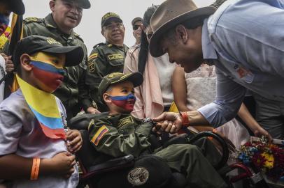 Colombian President Ivan Duque (R) shakes hands with a child wearing a police uniform as he arrives at the Workshops to build a country in Amaga, Antioquia department, Colombia on September 8, 2018.  Duque announced the suspension of talks with the ELN guerrilla until all hostages are released. / AFP PHOTO / JOAQUIN SARMIENTO