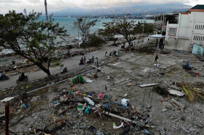 Survivors ride past debris in a devastated area in Palu, Indonesias Central Sulawesi on October 1, 2018, after an earthquake and tsunami hit the area on September 28.Indonesian volunteers began burying bodies in a mass grave with space for more than a thousand people on October 1, victims of a quake-tsunami that devastated swathes of Sulawesi and left authorities struggling to deal with the sheer scale of the disaster. / AFP PHOTO / JEWEL SAMAD