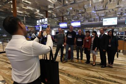 Pier Messaggio (4th-L), Italian eletronics designer poses with other passengers of flight SQ22, Singapore Airlines inaugural non-stop flight to New York with airport staff after checking in at Changi International Airport in Singapore on October 11, 2018. - Passengers were getting ready to board the worlds longest flight on October 11 -- a marathon 19 hours in the air between Singapore and New York. (Photo by ROSLAN RAHMAN / AFP)