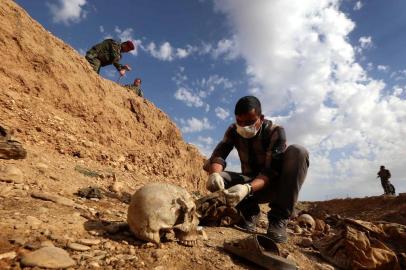 (FILES) In this file photo taken on February 03, 2015 An Iraqi man inspects, the remains of members of the Yazidi minority killed by the Islamic State (IS) jihadist group after Kurdish forces discovered a mass grave near the village of Sinuni, in the northwestern Sinjar area. - The Islamic State group left behind more than 200 mass graves in Iraq containing up to 12,000 victims that could hold vital evidence of war crimes, the UN said November 6, 2018.The United Nations in Iraq (UNAMI) and its human rights office said they had documented a total of 202 mass graves in parts of western and northern Iraq held by IS between 2014 and 2017. (Photo by Safin HAMED / AFP)