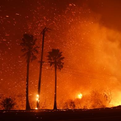 A power line catches fire as the Woolsey fire burns on both sides of Pacific Coast Highway (Highway 1) in Malibu, California, as night falls on November 9, 2018. About 75,000 homes have been evacuated in Los Angeles and Ventura counties due to two fires in the region. 