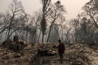 Jhonathan Clark walks in what was his house, destroyed by Camp fire, in Paradise, California, on November 15, 2018. - Jhonathan Clark was speechless, with his hands on his head he began to walk through the sea of rubble in which his house in Paradise became, a village massacred by fire. His great concern now is to find his brother Maurice, his sister in law and his six year old nephew, of whom he has had no news since hell began. Fire Camp claimed the lives of at least 63 people and 631 are reported missing, authorities said on November 15, 2018. (Photo by Javier TOVAR / AFP)