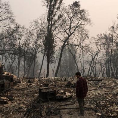 Jhonathan Clark walks in what was his house, destroyed by Camp fire, in Paradise, California, on November 15, 2018. - Jhonathan Clark was speechless, with his hands on his head he began to walk through the sea of rubble in which his house in Paradise became, a village massacred by fire. His great concern now is to find his brother Maurice, his sister in law and his six year old nephew, of whom he has had no news since hell began. Fire Camp claimed the lives of at least 63 people and 631 are reported missing, authorities said on November 15, 2018. (Photo by Javier TOVAR / AFP)