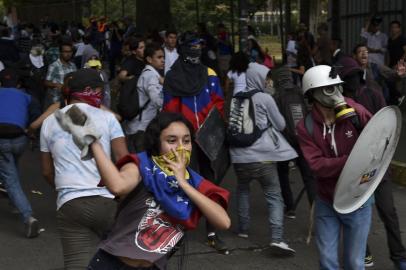 A student of Caracas Central University throws a stone at riot police during clashes, in the framework of a demonstration marking the University Student Day in Caracas, on November 21, 2018. (Photo by YURI CORTEZ / AFP)