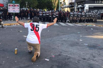 A supporter of River Plate gestures at riot police in the surroundings of the Monumental stadium in Buenos Aires following an attack on the Boca team bus before the all-Argentine Copa Libertadores second leg final match between River Plate and Boca Juniors on November 24, 2018. Saturdays superclasico Copa Libertadores final was postponed until Sunday following an attack on the Boca team bus that left players affected by smoke inhalation and broken glass.