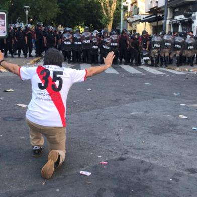 A supporter of River Plate gestures at riot police in the surroundings of the Monumental stadium in Buenos Aires following an attack on the Boca team bus before the all-Argentine Copa Libertadores second leg final match between River Plate and Boca Juniors on November 24, 2018. Saturdays superclasico Copa Libertadores final was postponed until Sunday following an attack on the Boca team bus that left players affected by smoke inhalation and broken glass.