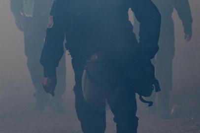  Mexicos Federal Police officers are seen through the smoke of tear gas thrown by the US Border Patrol to disperse Central American migrants -mostly Hondurans- after an alleged verbal dispute, near the El Chaparral border crossing in Tijuana, Baja California State, Mexico, close to the S-Mexico border, on November 25, 2018. - US officials closed the San Ysidro crossing point in southern California on Sunday after hundreds of migrants, part of the caravan condemned by President Donald Trump, tried to breach a fence from Tijuana, authorities announced. (Photo by GUILLERMO ARIAS / AFP)Editoria: POLLocal: TijuanaIndexador: GUILLERMO ARIASSecao: migrationFonte: AFPFotógrafo: STR