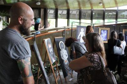 Exposição Santificados na Cãmara de Vereadores. Na foto, o artista fala sobre a mostra a uma visitante