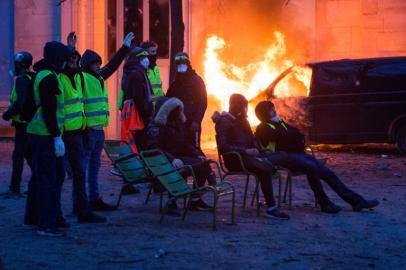 Demonstrators wearing Yellow vests (Gilets jaunes), stand next to a burning vehicle, on the Tuileries Garden, in front of the Musee de lOrangerie, during a protest against rising oil prices and living costs, in Paris on December 1, 2018. Police and anti-government protesters clashed near the Champs-Elysees and in other parts of central Paris on December 1 with demonstrators hurling rocks and paint at riot police who responded with tear gas. The clashes came as thousands took part in a third weekend of yellow vest protests which have morphed from anger over fuel taxes into a broader anti-government movement.