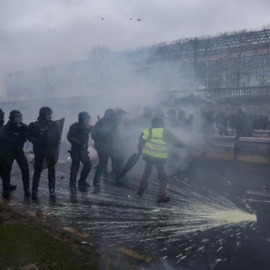 Yellow Vests (Gilets Jaunes in French) protesters clash with riot police forces against rising oil prices and living costs, in the French capital Paris on December 1, 2018. The yellow vest or Gilets jaunes movement is named after the high-visibility jackets which motorists are required to carry in their cars. The movement, organised through social media, has steadfastly refused to align with any political party or trade union and includes many pensioners and has been most active in small urban and rural areas where it has blocked roads, closed motorway toll booths, and even walled up the entrance to tax offices.