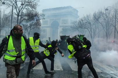 Yellow vests (Gilets jaunes) protesters hurl missiles during a protest close to the Arc de Triomphe against rising oil prices and living costs in the French capital Paris on December 1, 2018. Groups of masked protesters battled police through clouds of tear gas near Paris Champs Elysees as thousands took part in a third weekend of yellow vest demonstrations, which have morphed from anger over fuel taxes into a broader anti-government movement. 