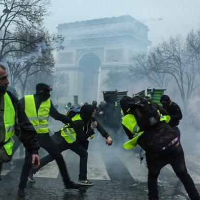 Yellow vests (Gilets jaunes) protesters hurl missiles during a protest close to the Arc de Triomphe against rising oil prices and living costs in the French capital Paris on December 1, 2018. Groups of masked protesters battled police through clouds of tear gas near Paris Champs Elysees as thousands took part in a third weekend of yellow vest demonstrations, which have morphed from anger over fuel taxes into a broader anti-government movement. 