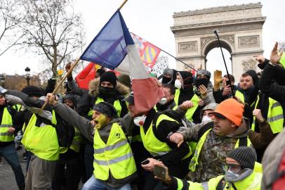 Protestors wearing yellow vest (gilet jaune) gesture on December 8, 2018 near the Arc de Triomphe in Paris during a protest against rising costs of living they blame on high taxes. - Paris was on high alert on December 8 with major security measures in place ahead of fresh yellow vest protests which authorities fear could turn violent for a second weekend in a row. (Photo by Eric FEFERBERG / AFP)