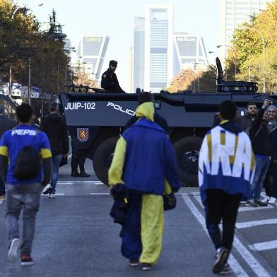 Riot Police officers stand guard as supporters of Boca Juniors walk along the Paseo de la Castellana (The Castilians Mall) south of the Santiago Bernabeu stadium in Madrid, hours before the start of the second leg match of the all-Argentine Copa Libertadores final between River Plate and Boca Juniors, on December 9, 2018. (Photo by OSCAR DEL POZO / AFP)