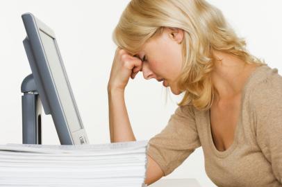 Frustrated Woman at Computer With Stack of PaperImportação Donnahttp://revistadonna.clic