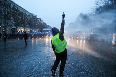  A protester wearing a yellow vest (gilet jaune) gestures in front of police forces during a demonstration against rising costs of living blamed on high taxes on the Champs-Elysees in Paris, on December 15, 2018. - The Yellow Vests (Gilets Jaunes) movement in France originally started as a protest about planned fuel hikes but has morphed into a mass protest against Presidents policies and top-down style of governing. (Photo by Zakaria ABDELKAFI / AFP)Editoria: POLLocal: ParisIndexador: ZAKARIA ABDELKAFISecao: social issues (general)Fonte: AFPFotógrafo: STR