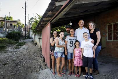 PORTO ALEGRE, RS, BRASIL, 26-12-2018: O gerente de recepção do hotel Sheraton, Eduardo Finamor, a mulher dele, Daniela Finamor (D), o filho do casal, Arthur Finamor, a cunhada Débora dos Santos (E), a irmã Eliane Finamor, o pai João Finamor, Mara Finamor e Rafaella Lopes, no beco de chão batido em frente à casa onde Eduardo viveu com a família, na Vila Pinto, no bairro Bom Jesus. Finamor começou a trabalhar no hotel graças a uma ONG que acenou com a possibilidade. Ele foi repositor de frigobar, mensageiro e porteiro, entre outras atividades, até ser promovido a gerente neste ano. (Foto: Mateus Bruxel / Agência RBS)